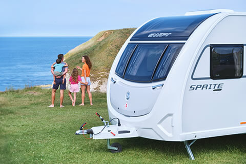 Family stood outside a touring caravan by the coast