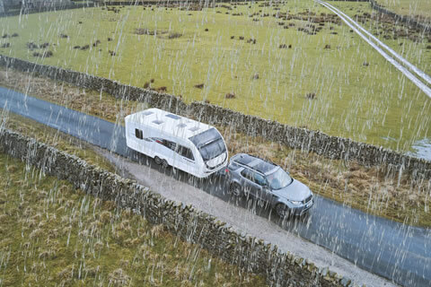 Driver towing a caravan in heavy rain